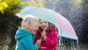 Children laughing under umbrella - Kids in East London enjoy April showers