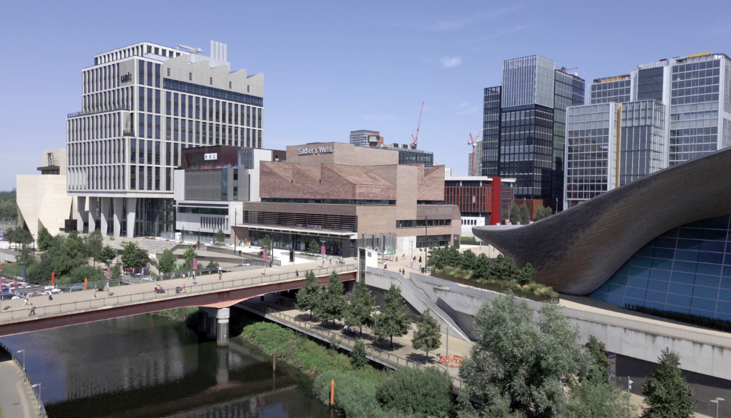 An aerial view of Sadler's Wells East, the new cultural hub for dance in Stratford's Queen Elizabeth Olympic Park, showcasing the modern architecture and its surrounding vibrant East Bank development.