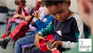 Strings Club Summer Holiday Camps in East London offer children an introduction to musical instruments. A boy concentrates while learning to play the ukulele