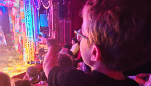An image of a boy with achondroplasia pointing at a colourful stage photographed from Stratford East panto Pinocchio from last year. An examples of the kind of things you'll find to do with the Kids in East London London in this round up