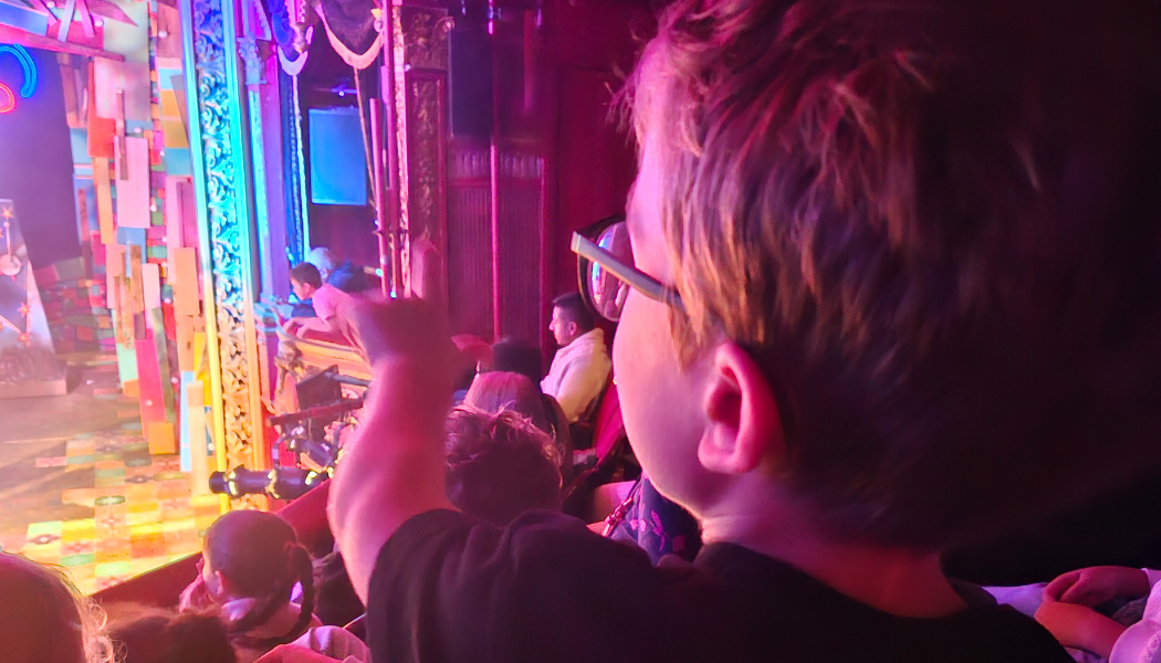 An image of a boy with achondroplasia pointing at a colourful stage photographed from Stratford East panto Pinocchio from last year. An examples of the kind of things you'll find to do with the Kids in East London London in this round up