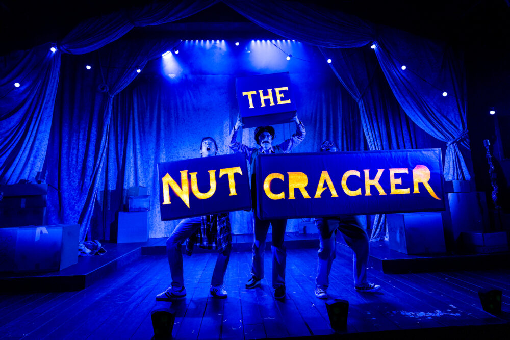 The Nutcracker words held up by characters from the performance in a deep cobalt blue set