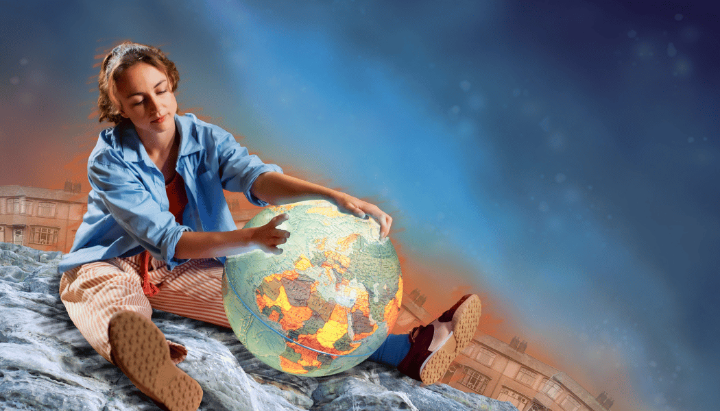 A woman with her tied back examines a glowing globe while sitting on a sphere from Myth Monsters SEND friendly performance